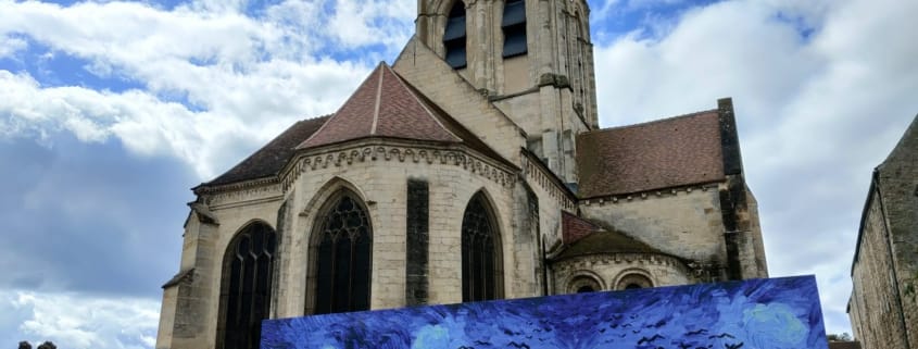Kościół Notre-Dame-de-l'Assomption w Auvers-sur-Oise z reprodukcją obrazu Van Gogha Pole pszenicy z krukami